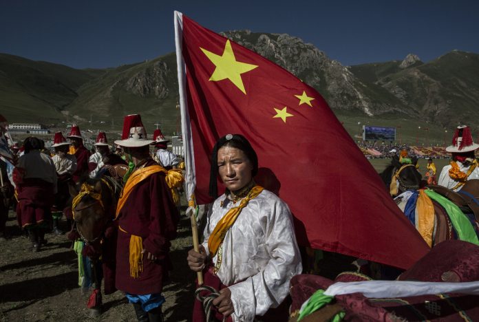 Latest news on Tibet and China A Tibetan man holds a Chinese flag in Tibetan Plateau in Yushu County, Qinghai, China | Kevin Frayer/Getty Images