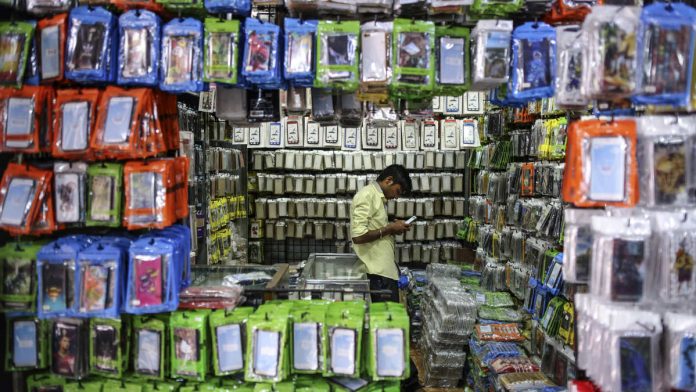 Latest news on GST | ThePrint A vendor uses a smartphone at a wholesale stall selling mobile phone accessories (Representational image)