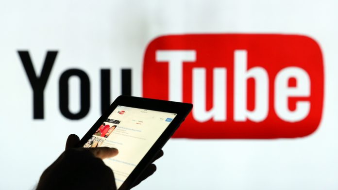 Latest news on YouTube| ThePrint.in A man is seen as a silhouette as he checks a mobile device whilst standing against an illuminated wall bearing YouTube Inc.s logo in this arranged photograph in