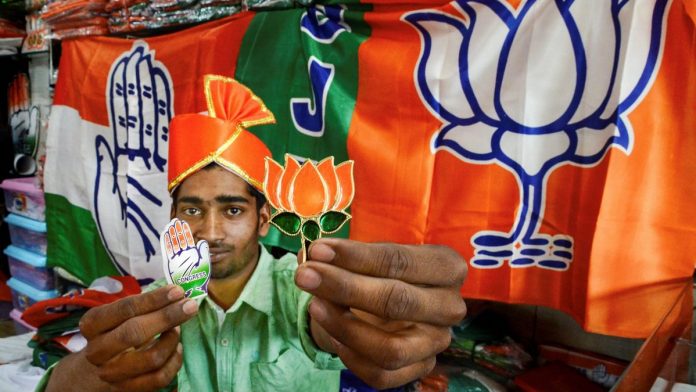 General Elections 2019 A shopkeeper poses with political parties' campaign materials ahead of Lok Sabha elections 2019 | PTI