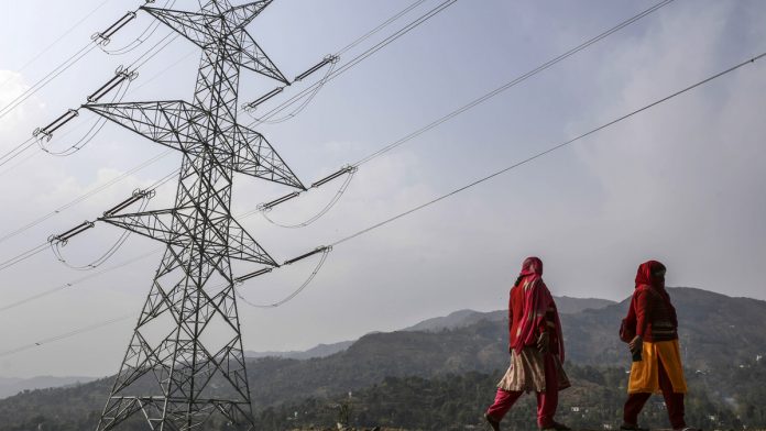 Latest news on Saubhagya scheme | theprint.in Woman walk past a transmission tower in Jammu and Kashmir | Dhiraj Singh/Bloomberg