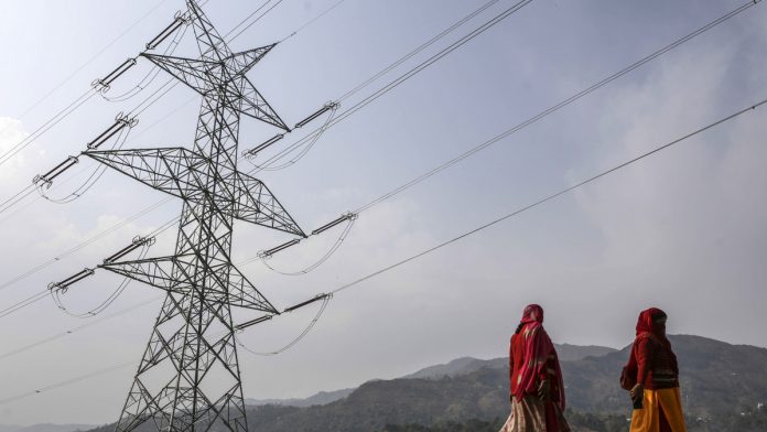 India's Weak Power Demand Points to More Slowdown Pain Ahead Woman walk past a transmission tower in Rajouri district, Jammu and Kashmir |Dhiraj Singh/Bloomberg