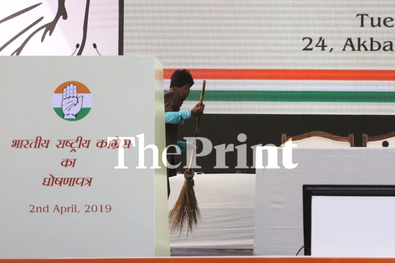 A party supporter gives a final brush to the stage before the manifesto launch at AICC headquarters | Praveen Jain/ThePrint