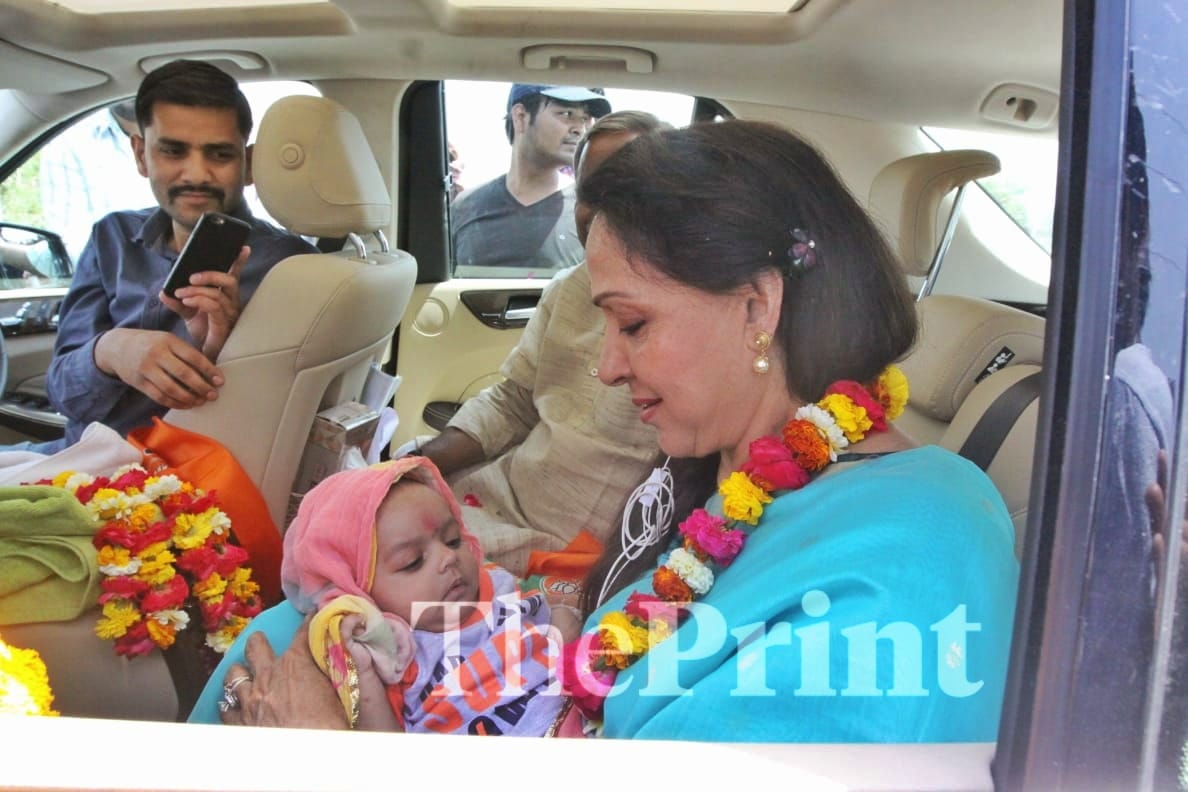 Hema Malini holds a child during her visit to Jait village