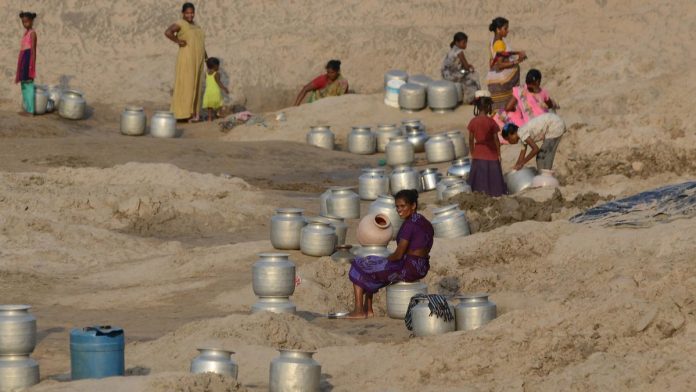 Village women wait with their metal pitchers for the water to get filled in the holes they dug in a dried-up pond during this summer in Palletummalapalem village near Machilipatnam in Andhra Pradesh Village women wait with their metal pitchers for the water to get filled in the holes they dug in a dried-up pond during this summer in Palletummalapalem village near Machilipatnam in Andhra Pradesh
